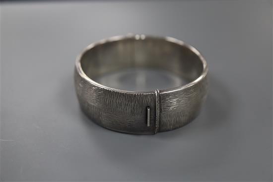 A 1970s textured silver hinged bracelet, with checkered decoration, by Rigby & Wilson, gross 46 grams.